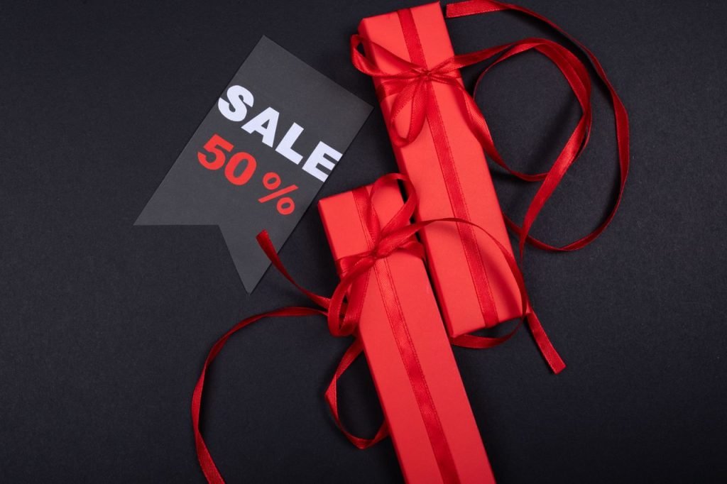 Red gift boxes with ribbons and a prominent 50% sale sign on black background.